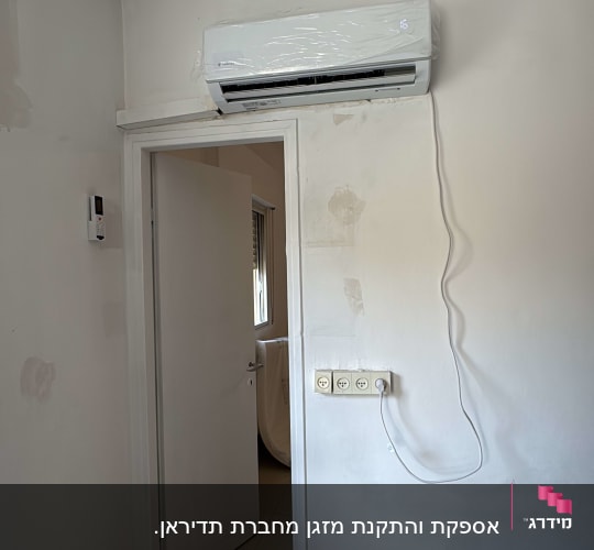מזגן מותקן על קיר עם כבל חשמל מחובר